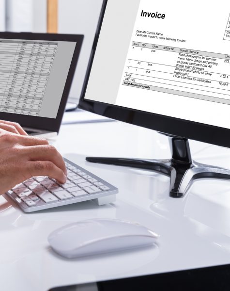 Businessperson Checking Invoice On Computer Close-up Of A Businessperson's Hand Checking Invoice On Computer At Workplace